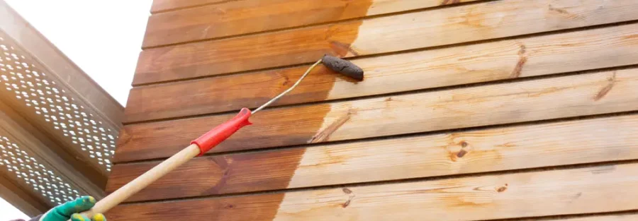 Công nhân đang sơn phủ lớp bảo vệ lên bề mặt gỗ bằng con lăn
