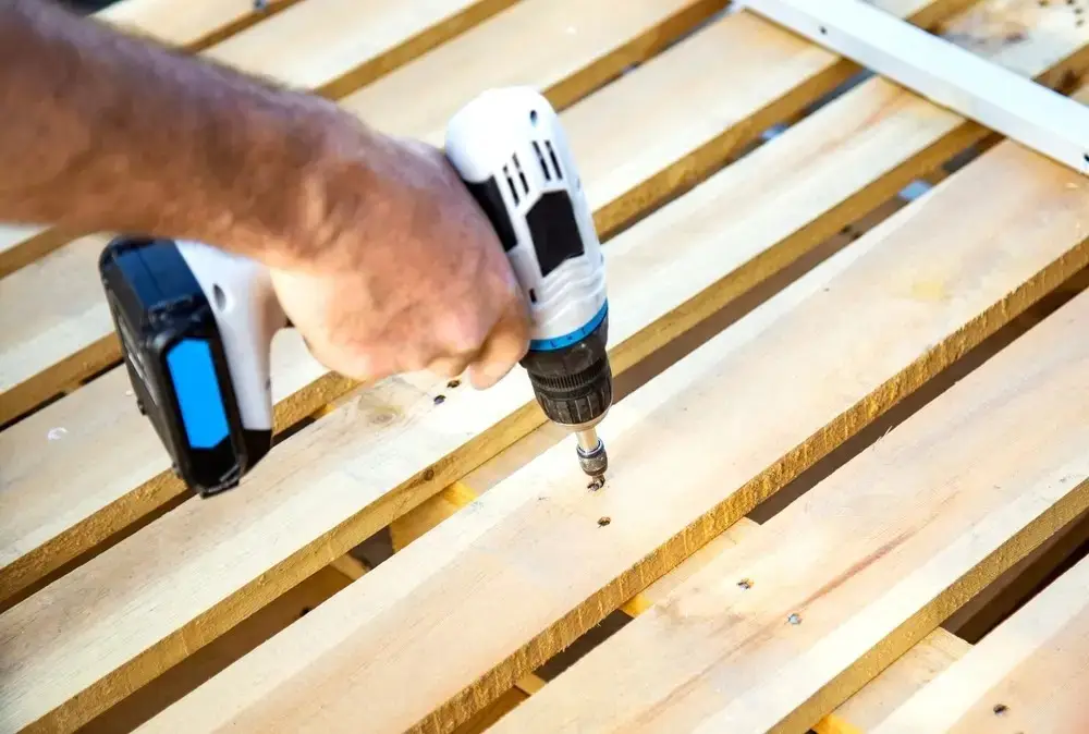 Người thợ mộc dùng máy khoan để đóng đinh cho pallet gỗ