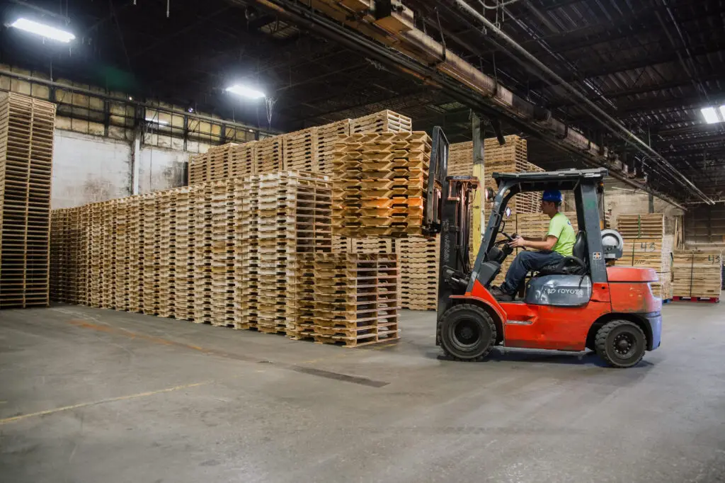 Xe nâng di chuyển pallet gỗ trong kho hàng công nghiệp